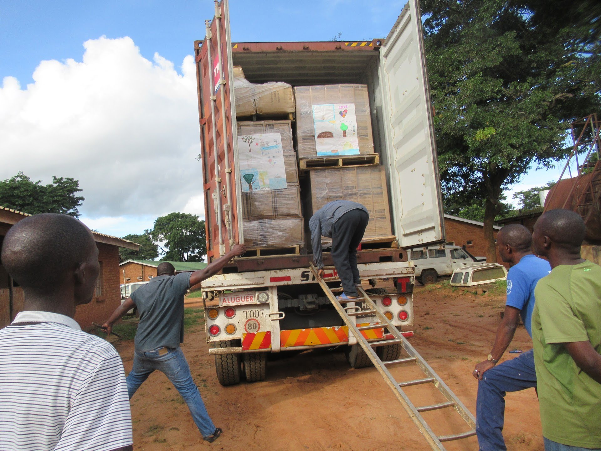 Volunteers in Malawi unloading a shipping container of donated medical supplies from a delivery truck