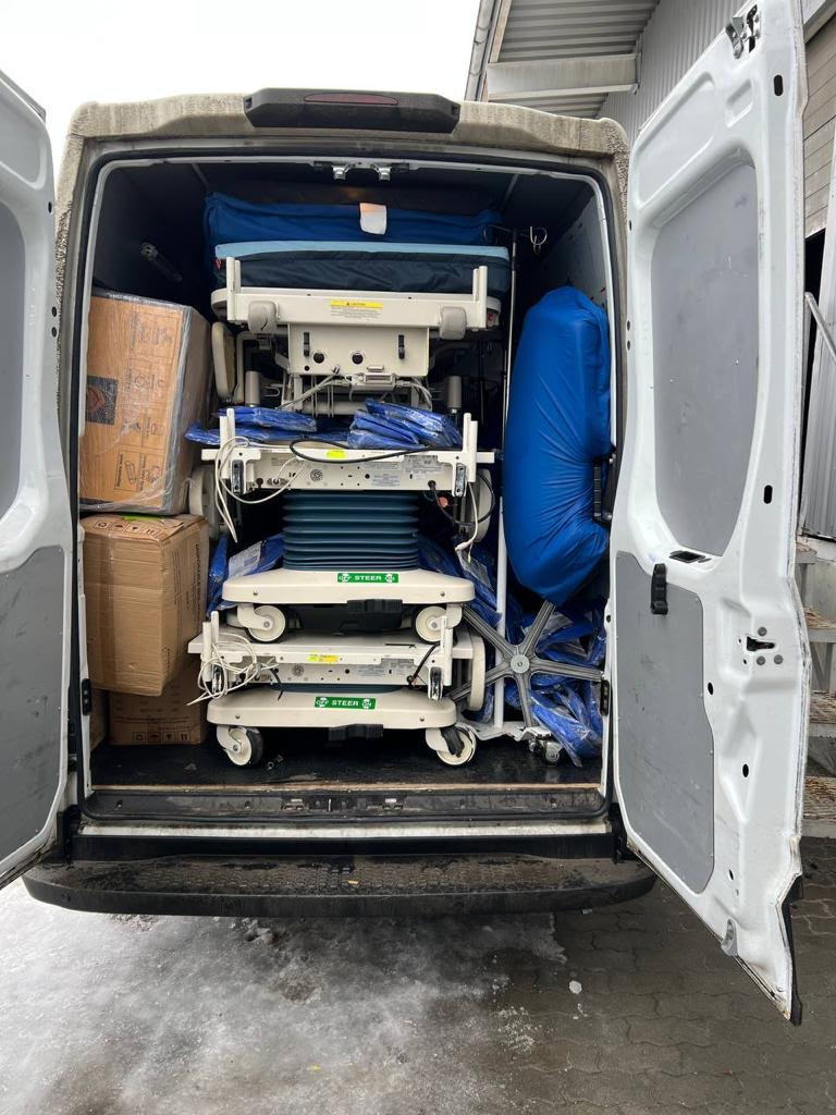 Hospital beds, stretchers, and donated medical equipment loaded into a delivery van for transport to the warehouse